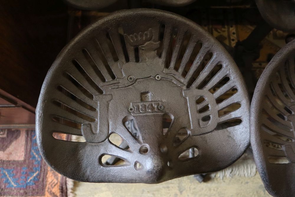 A set of six painted cast metal tractor seat stools, width 37cm depth 30cm height 64cm